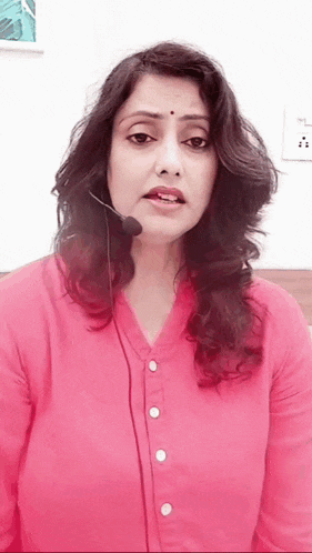 a woman wearing a pink shirt and a microphone