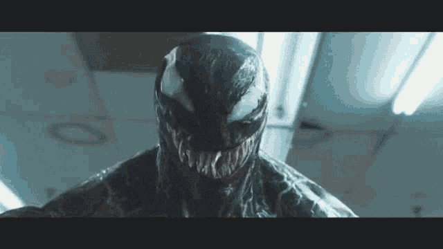 a close up of venom 's face in a room with a ceiling light .