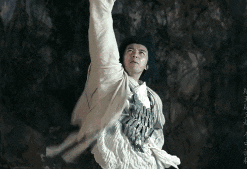a man in a white shirt and black hat is doing a karate move