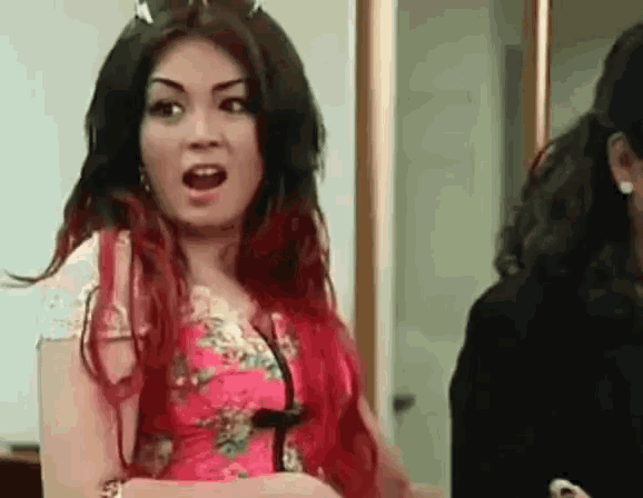 a woman with red hair and a pink dress is making a funny face .