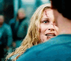 a woman with a scar on her face is looking at a man in a blue shirt .