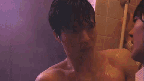 two men are kissing in a bathroom with a tiled wall in the background