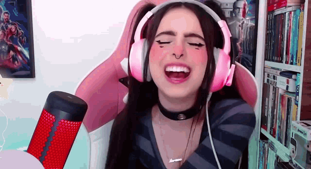 a woman wearing pink headphones is sitting in front of a bookshelf