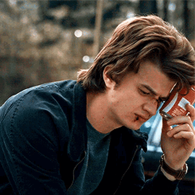 a man is talking on a cell phone while holding a can of soda in his hand