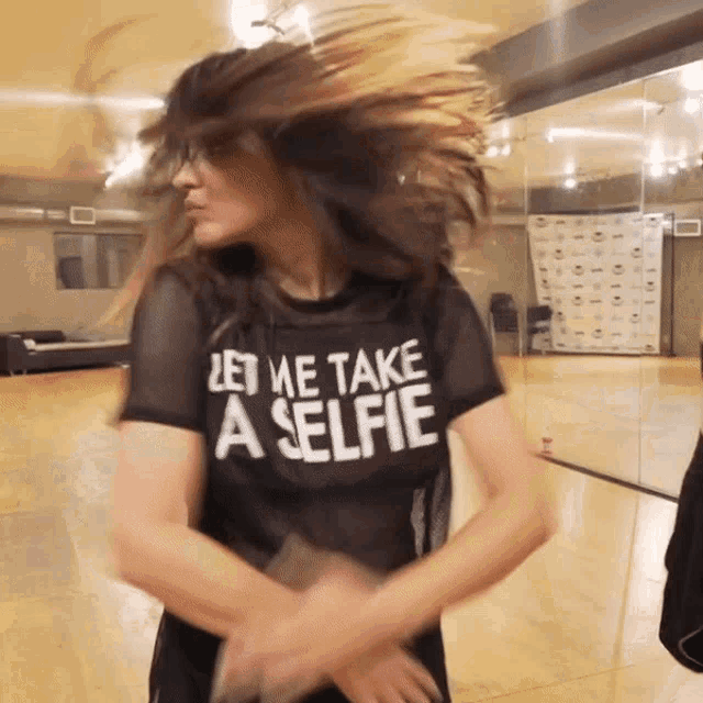 a woman wearing a shirt that says " let me take a selfie "