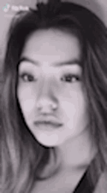 a black and white photo of a young woman 's face with long hair .