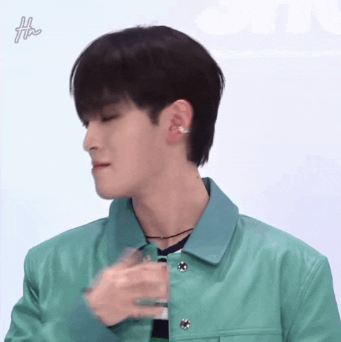 a man wearing a green jacket has the letter h on his earring