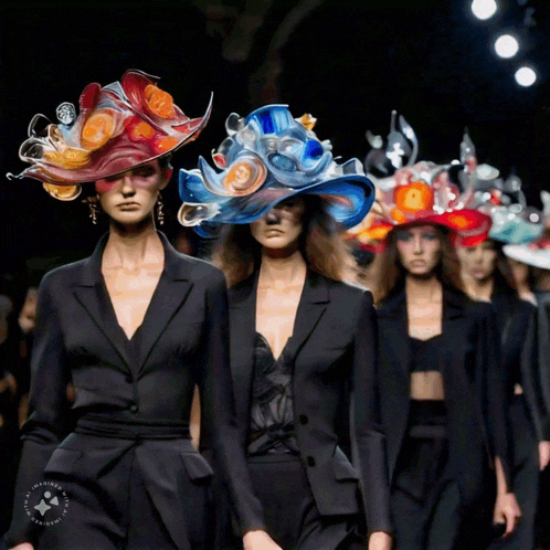 a group of women are walking down a runway wearing colorful hats and jackets