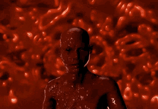 a bald man is covered in red liquid and looks like a monster