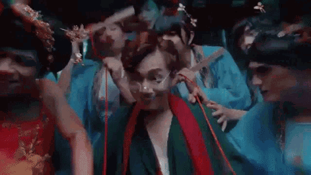 a group of people are standing around a man in a green robe .