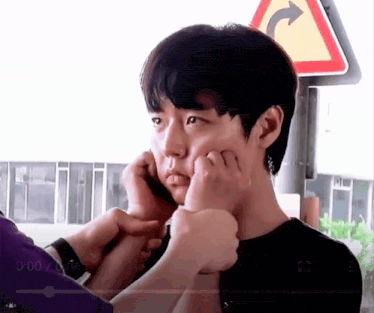 a close up of a person putting a bandage on a young man 's face .