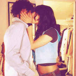 a man and a woman are kissing in front of a closet