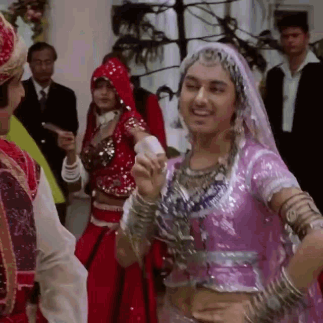 a woman in a pink dress is dancing in front of a man in a red and white dress .