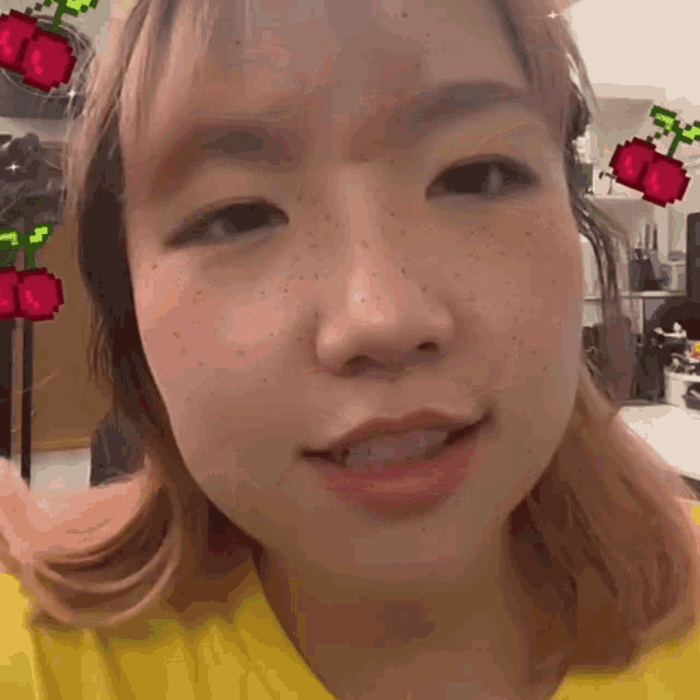 a close up of a girl 's face with a pixelated cherry behind her
