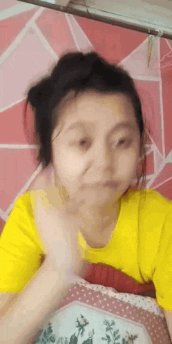 a young girl in a yellow shirt is laying on a bed making a funny face .