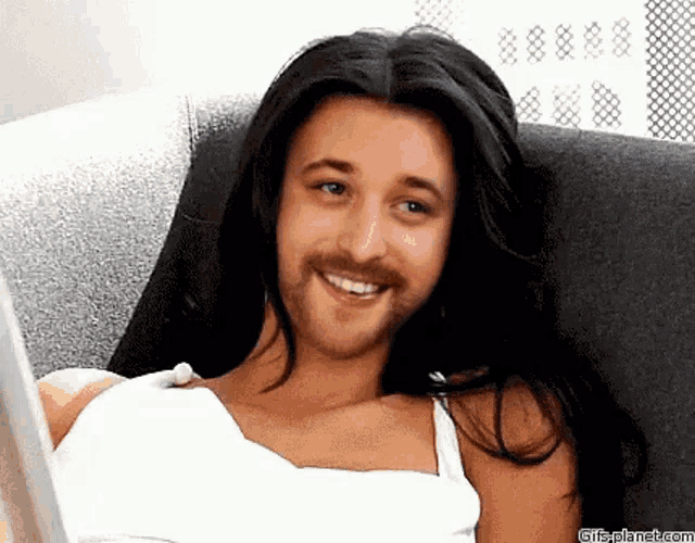 a man with long hair and a beard is laying on a couch .