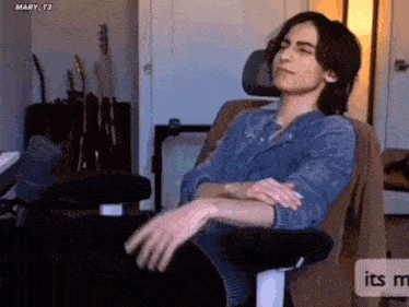 a man is sitting in a chair with his eyes closed and his hands folded .