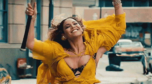 a woman in a yellow dress is holding a stick in her hand .