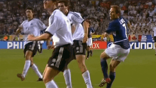 a group of soccer players are playing on a field with hyundai advertisements in the background .