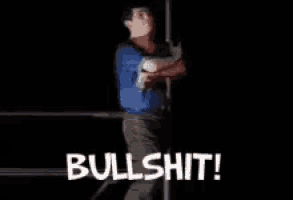 a man in a blue shirt is standing next to a pole with the word bullshit written on the bottom