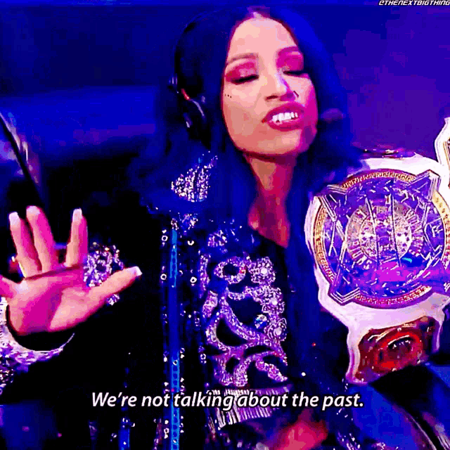 a woman wearing headphones is holding a championship belt and saying we 're not talking about the past