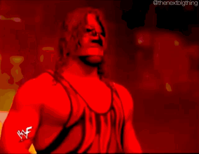 a man in a red and black wrestling outfit is standing in front of a sign that says raw kane .