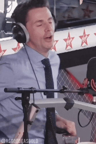 a man wearing headphones is singing into a microphone in front of a virgin logo