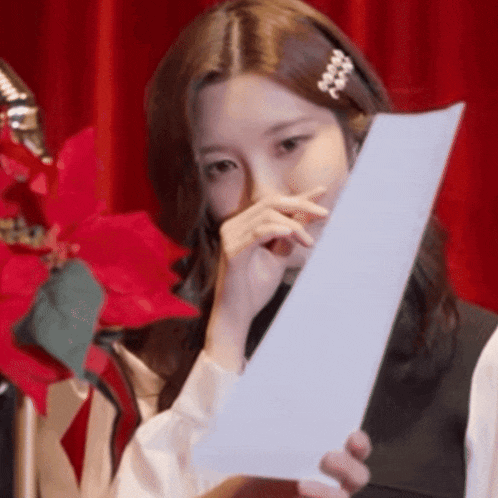 a woman is covering her face with a piece of paper .