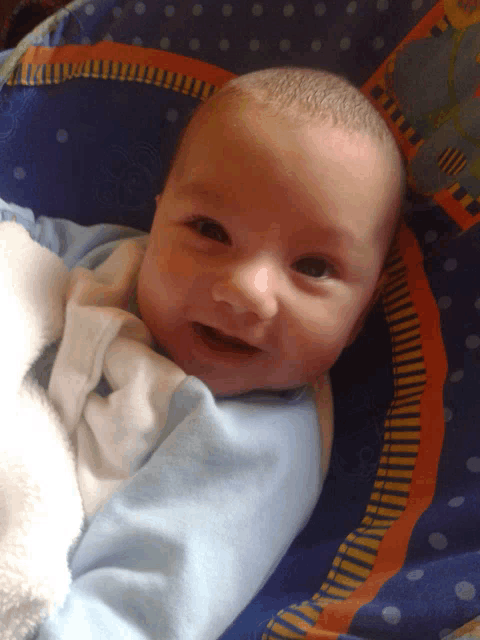 a baby is laying in a blue and orange polka dot crib