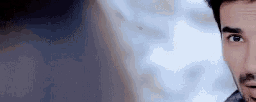a close up of a man 's face with a beard and a blue background .