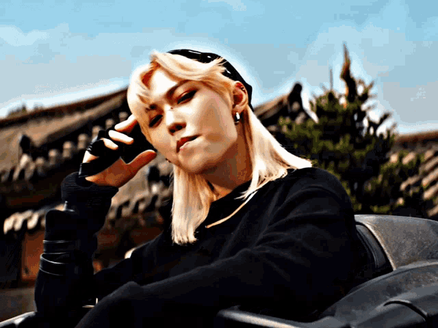 a man with blonde hair is wearing a black sweater