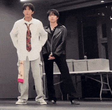 two men are standing next to each other and one has a tie on