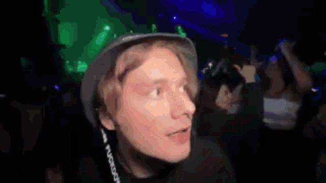 a man wearing a hat is making a funny face in a dark room with a green light behind him .