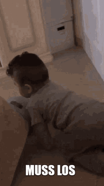 a baby is crawling on the floor in a room with the words muss los written on the bottom .