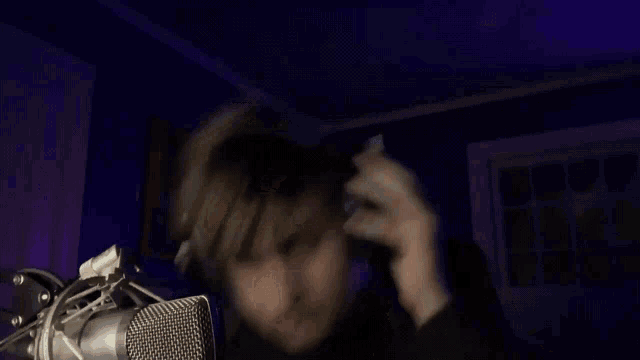 a man wearing headphones is singing into a microphone in a dark room