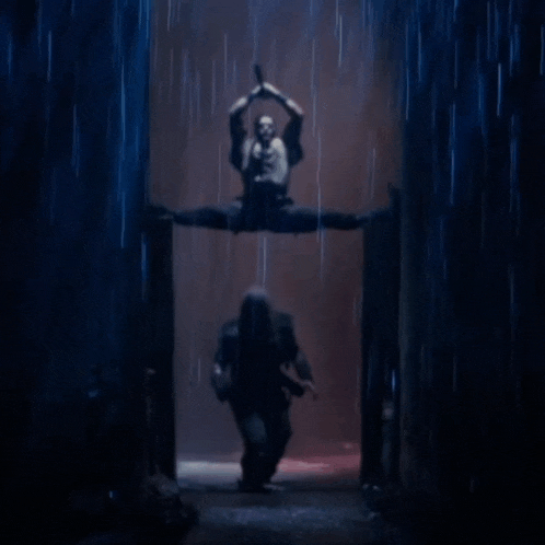 a man is standing in the rain while a woman is doing a split in the air