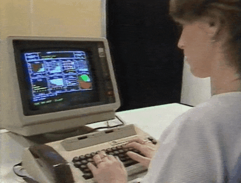 a woman is typing on a keyboard while looking at a computer monitor