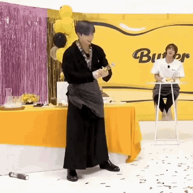 a man in an apron is standing in front of a table with a yellow table cloth .