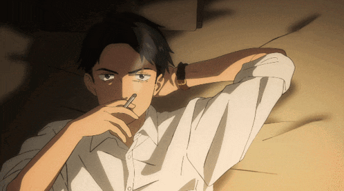 a man in a white shirt is laying on a bed with his hand on his nose