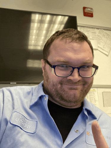 a man wearing glasses and a name tag that says matt anthony is giving a thumbs up