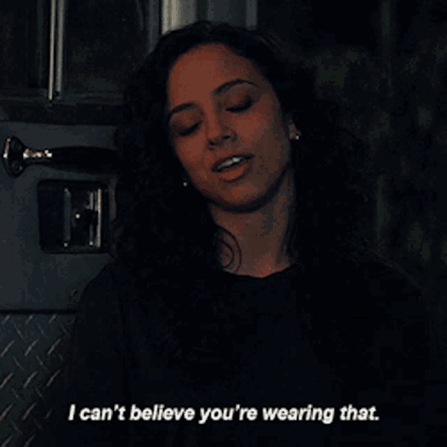 a woman in a black shirt is saying i can 't believe you 're wearing that