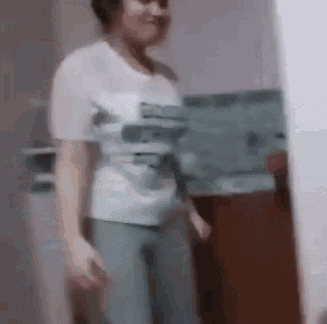 a woman in a white shirt is standing in a kitchen .