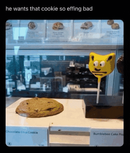 a chocolate chip cookie and a bumblebee cake pop are on display in a bakery