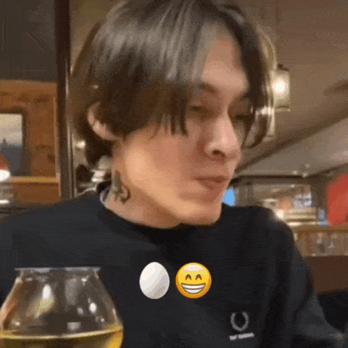 a man with a tattoo on his neck is sitting at a table with a glass of wine and a smiley face .