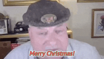 a man wearing a beret is saying merry christmas while looking at the camera .