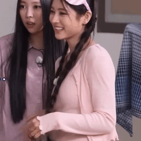 two women are standing next to each other in a room and smiling .