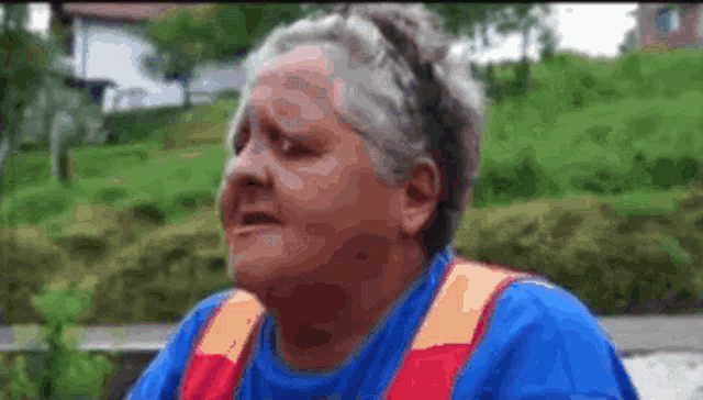 a woman in a blue shirt and orange vest is sitting on a bench with her eyes closed .