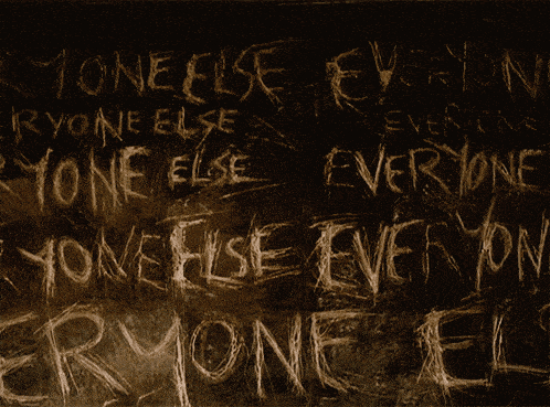 the word everyone is written in white chalk on a dark wall
