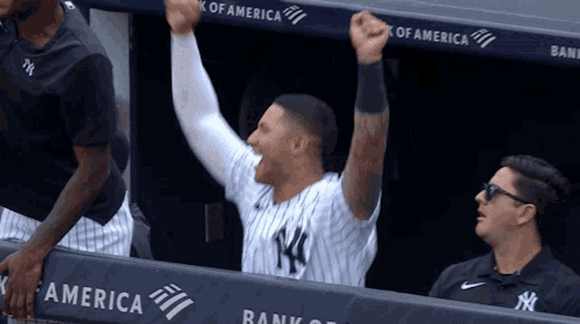 a man in a ny yankees uniform holds his fist up in the air