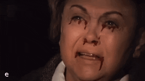 a close up of a woman 's face with blood coming out of her nose and eyes .